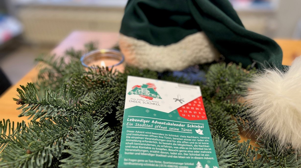 Flyer "Adventskaleender Schinkel" liegt auf weihnachtlich dekoriertem Tisch. 